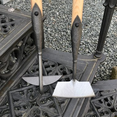 Zwei handgeschmiedete DeWit Hacken mit langem Stiel auf einem gusseisernen Gitter